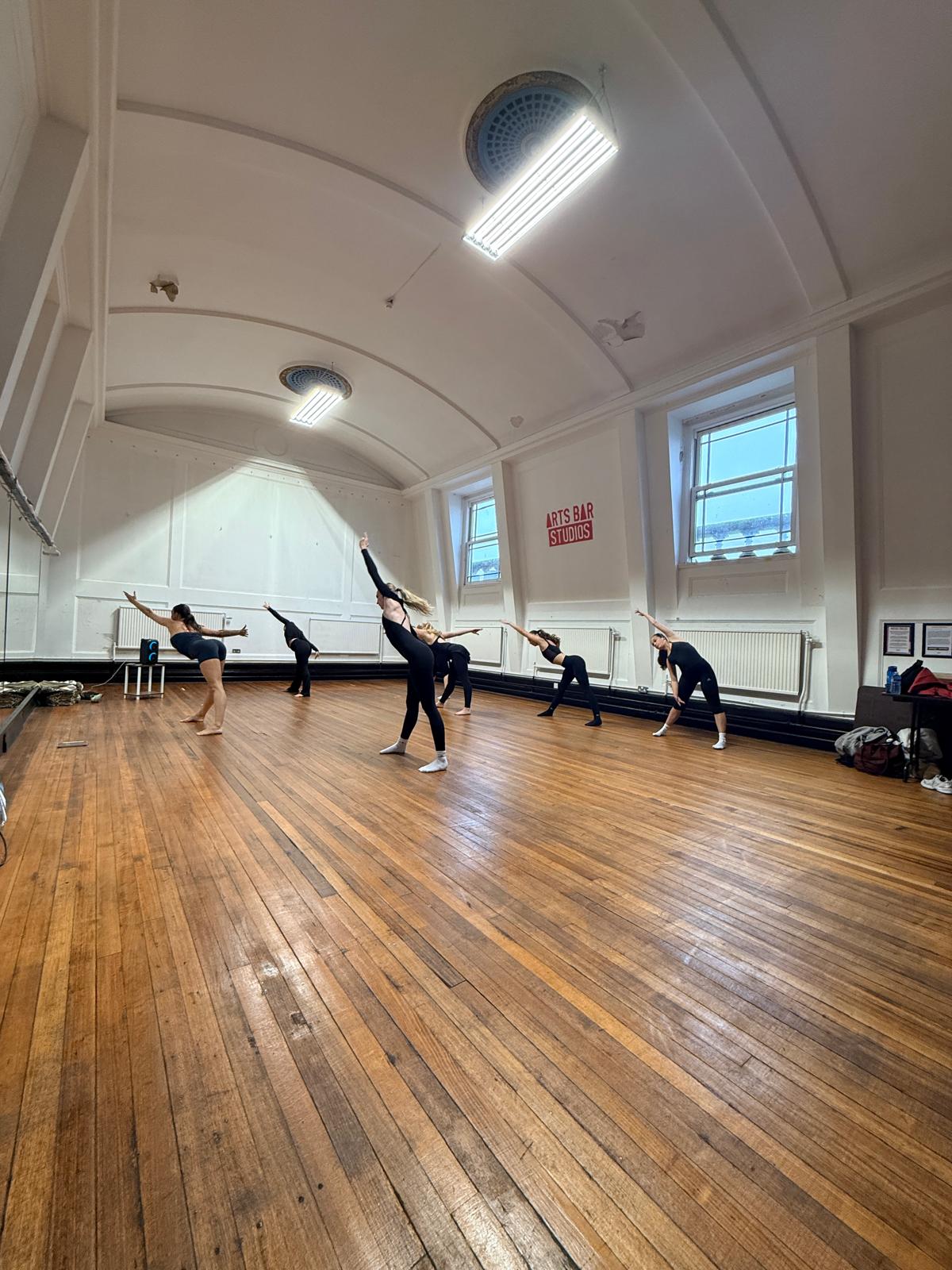 Performers working on dance technique in the studio